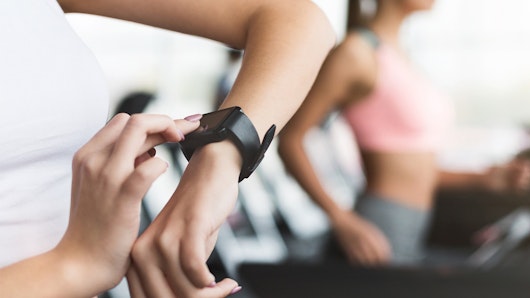 Sportswoman looking at smartwatch at gym.