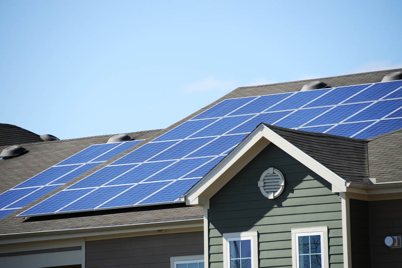 Solar panels on roof of house against blue sky.