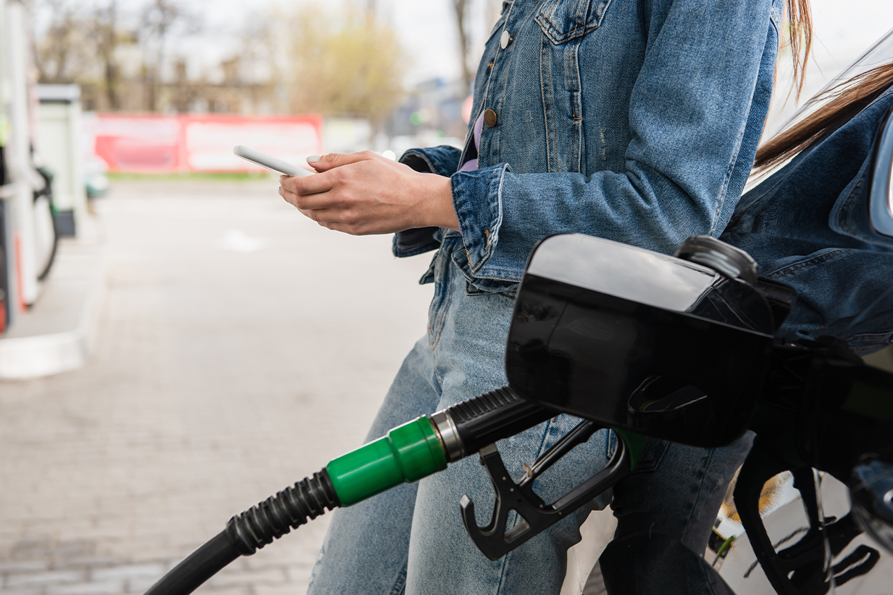 Woman using phone at petrol station.