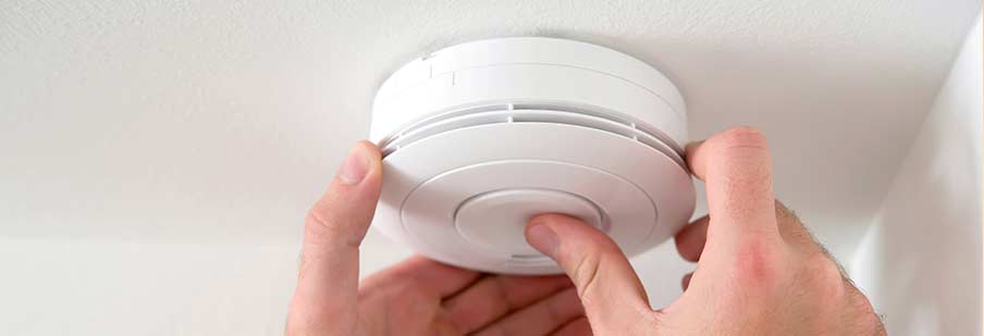 man removing smoke alarm from ceiling
