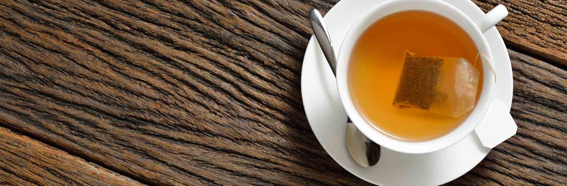 Tea bag in white tea cup with spoon and saucer.