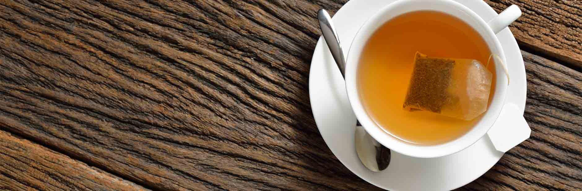 Tea bag in white tea cup with spoon and saucer.