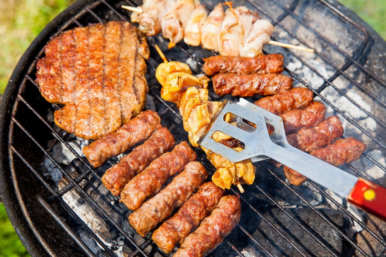 Photography of meat and veggies cooking on a barbecue.