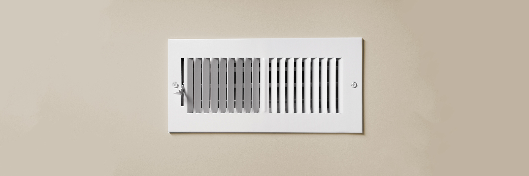 A cooling vent register on the wall of a home, with open lever.