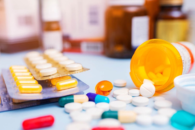 Photo of pill trays and bottles with spilled pills on table.