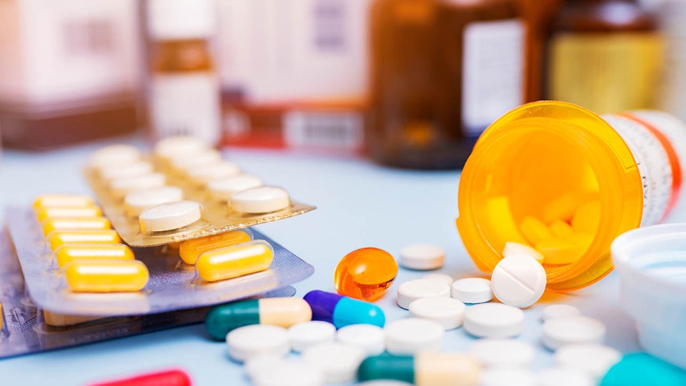 Photo of pill trays and bottles with spilled pills on table.