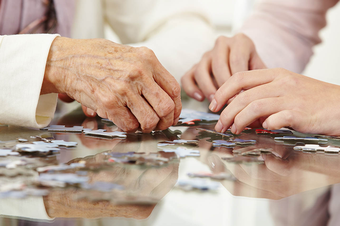 Older woman completing puzzle with younger woman.