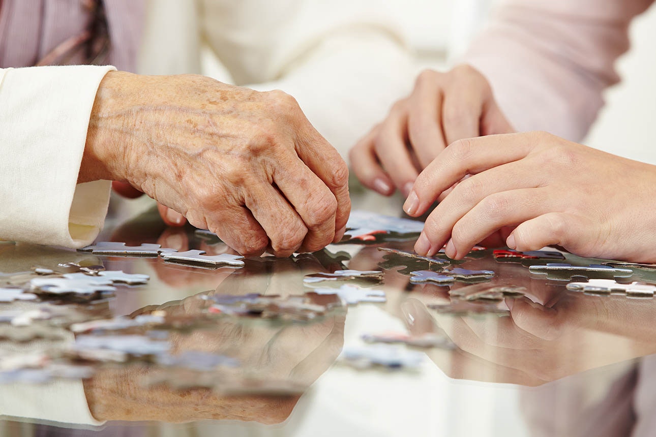 Older woman completing puzzle with younger woman.
