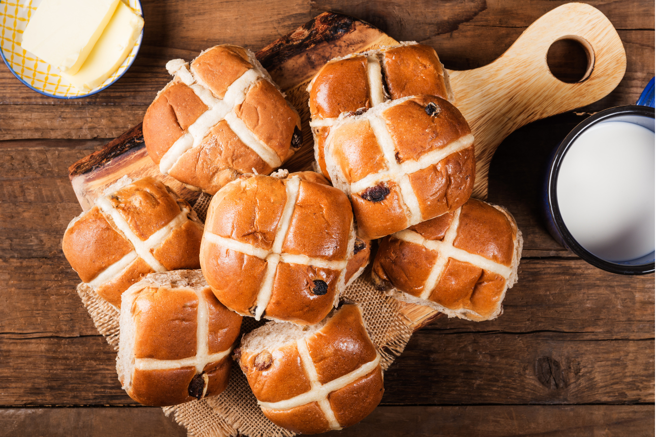 Hot cross buns with a small bowl of butter.