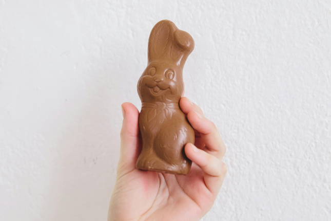 A person's hand holds up a chocolate easter bunny