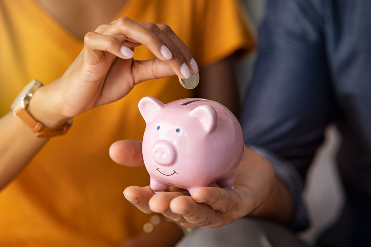 Person putting coin in piggy bank.