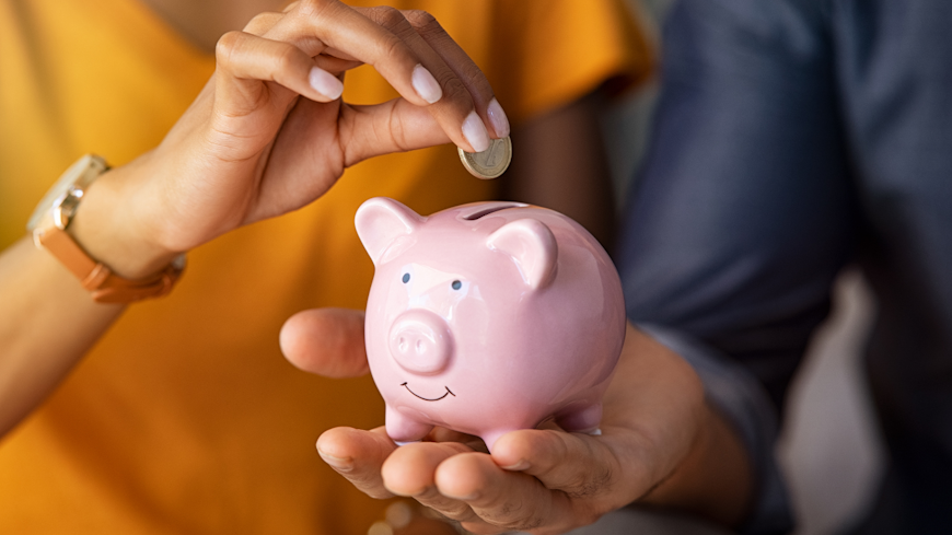 Person putting coin in piggy bank.