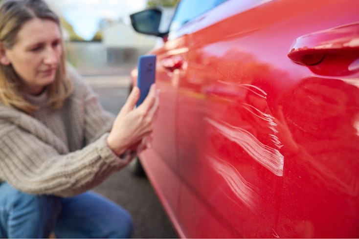 Consumer nz website promo image  a woman takes a photo of damage caused to a car for insurance purposes width