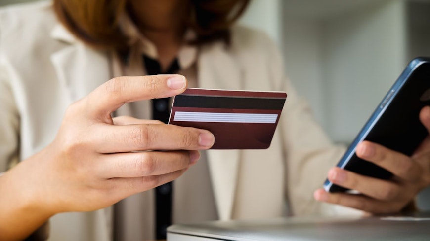 Woman holding a card and phone