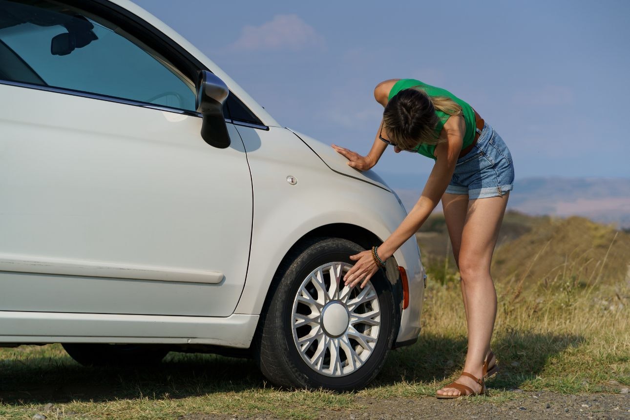 Image of a woman touching her car tyres