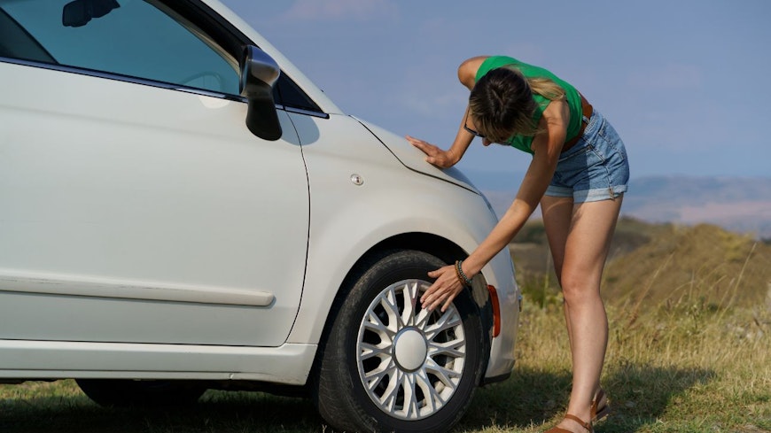 Image of a woman touching her car tyres