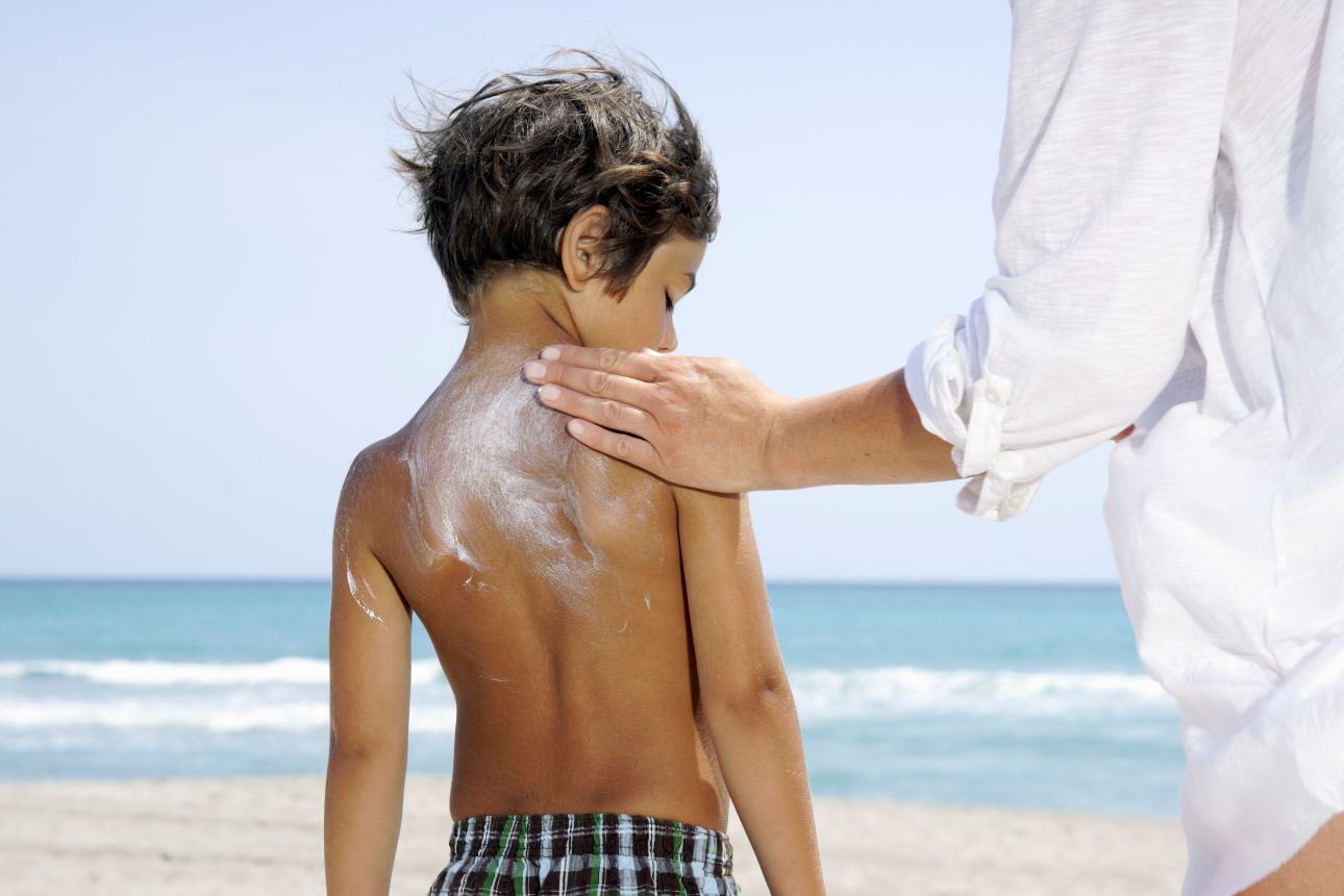 Image of woman applying sunscreen on boy