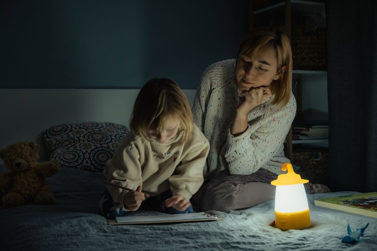 Image of a mother and daughter with a lantern in a dark room.