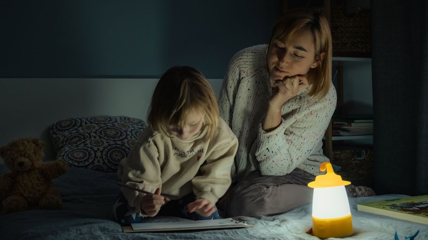 Image of a mother and daughter with a lantern in a dark room.