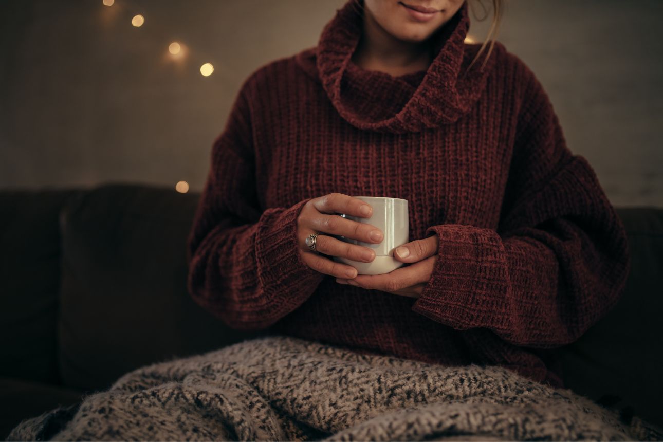 Image of a woman in a jumper holding warm drink