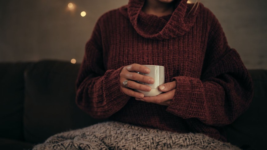 Image of a woman in a jumper holding warm drink