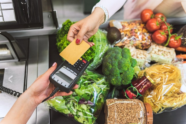 Image of person paying for groceries at the checkout