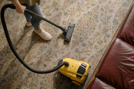 Person using vacuum cleaner at home.