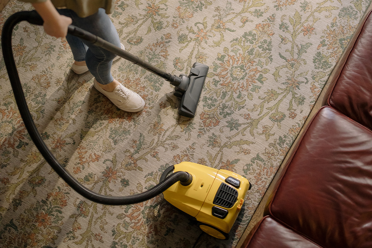 Person using vacuum cleaner at home.