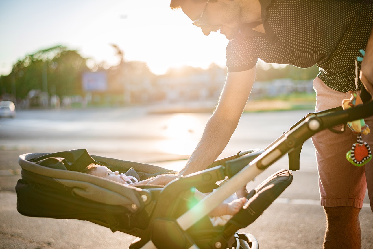 Father and baby in stroller walking on sunset.