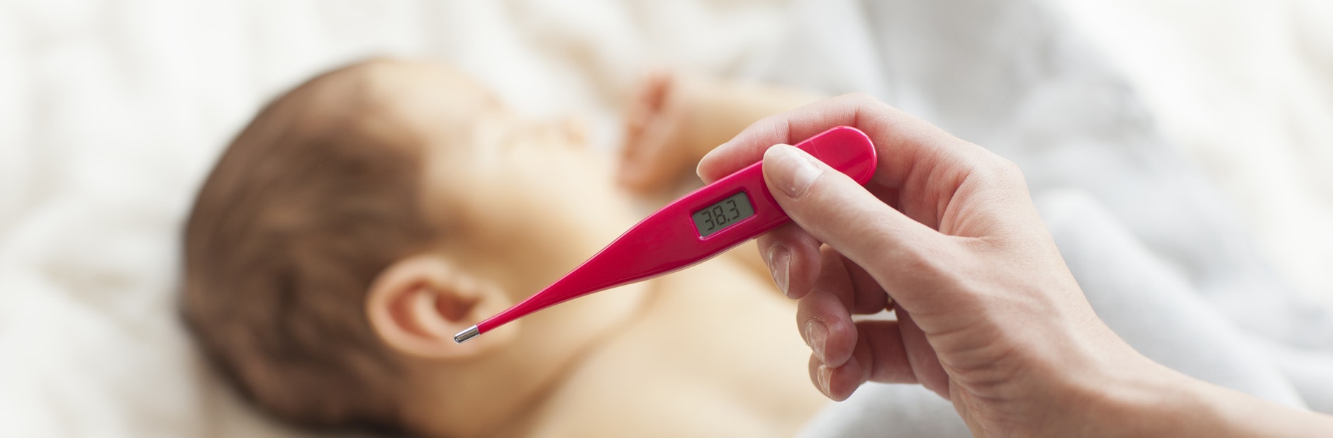 Holding thermometer over baby.