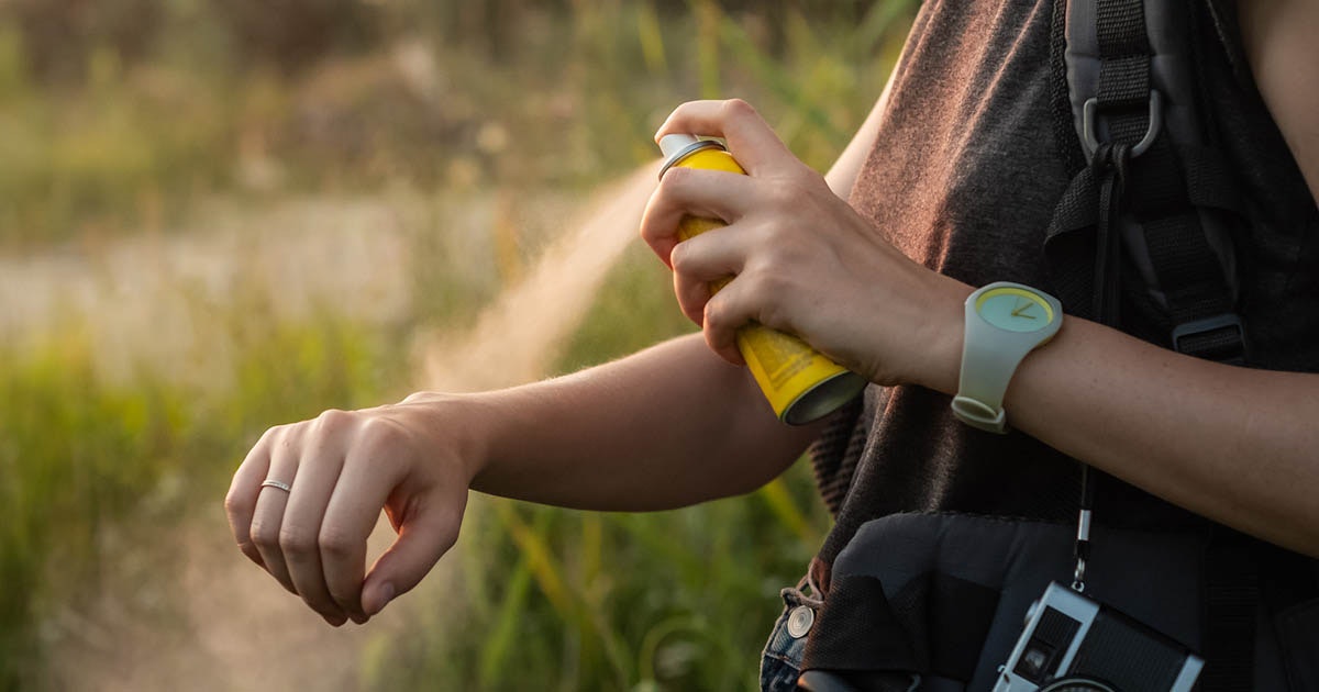 Close-up of young tourist applying mosquito spray on arms.