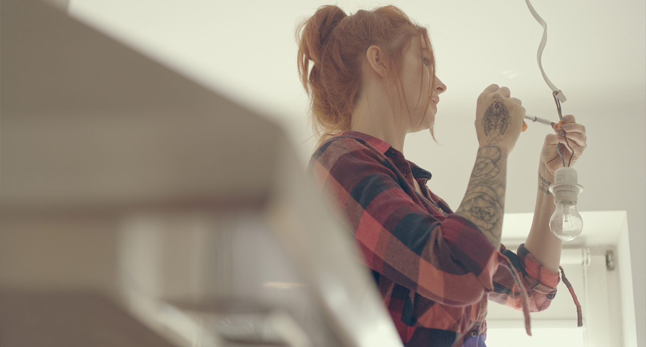Young manual worker repairing light in renovating apartment.