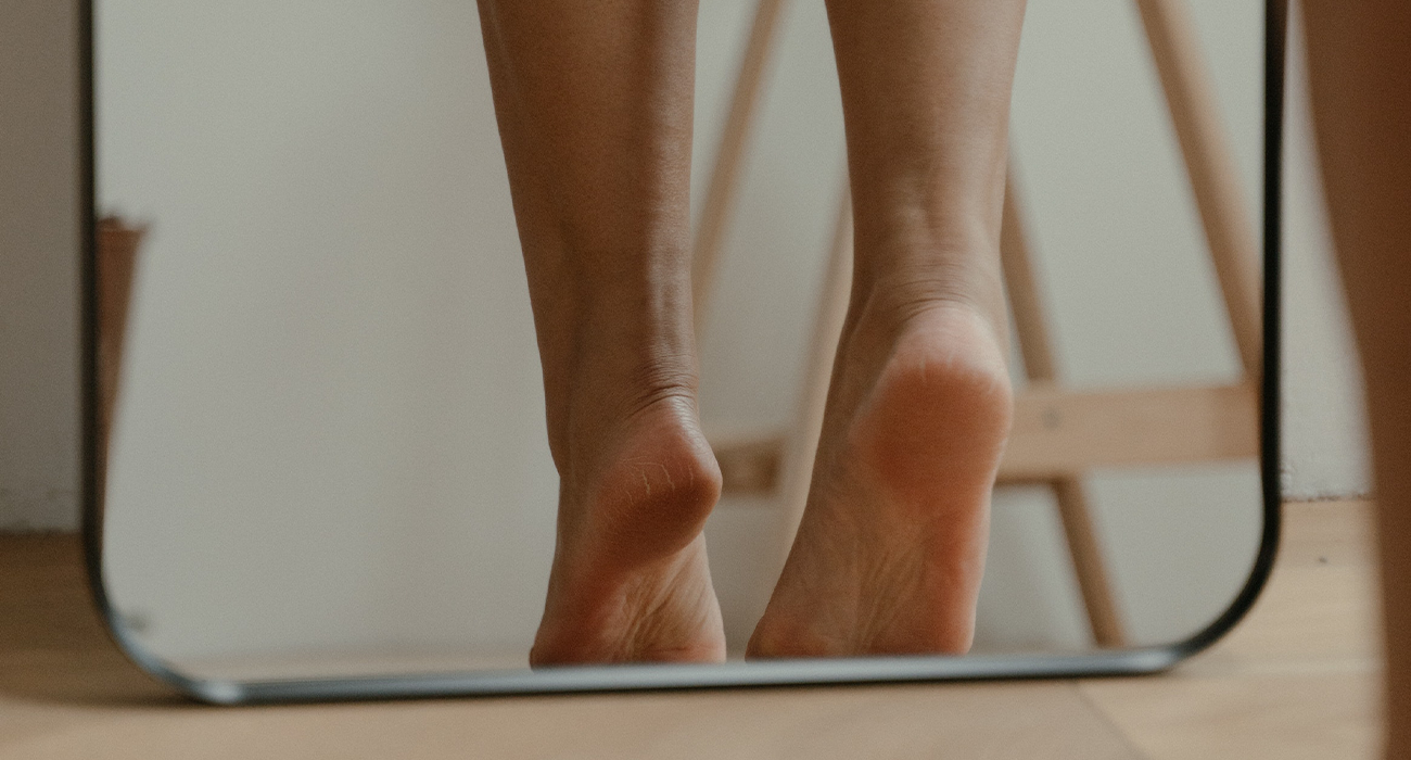 Photo of woman's legs and feet on mirror.