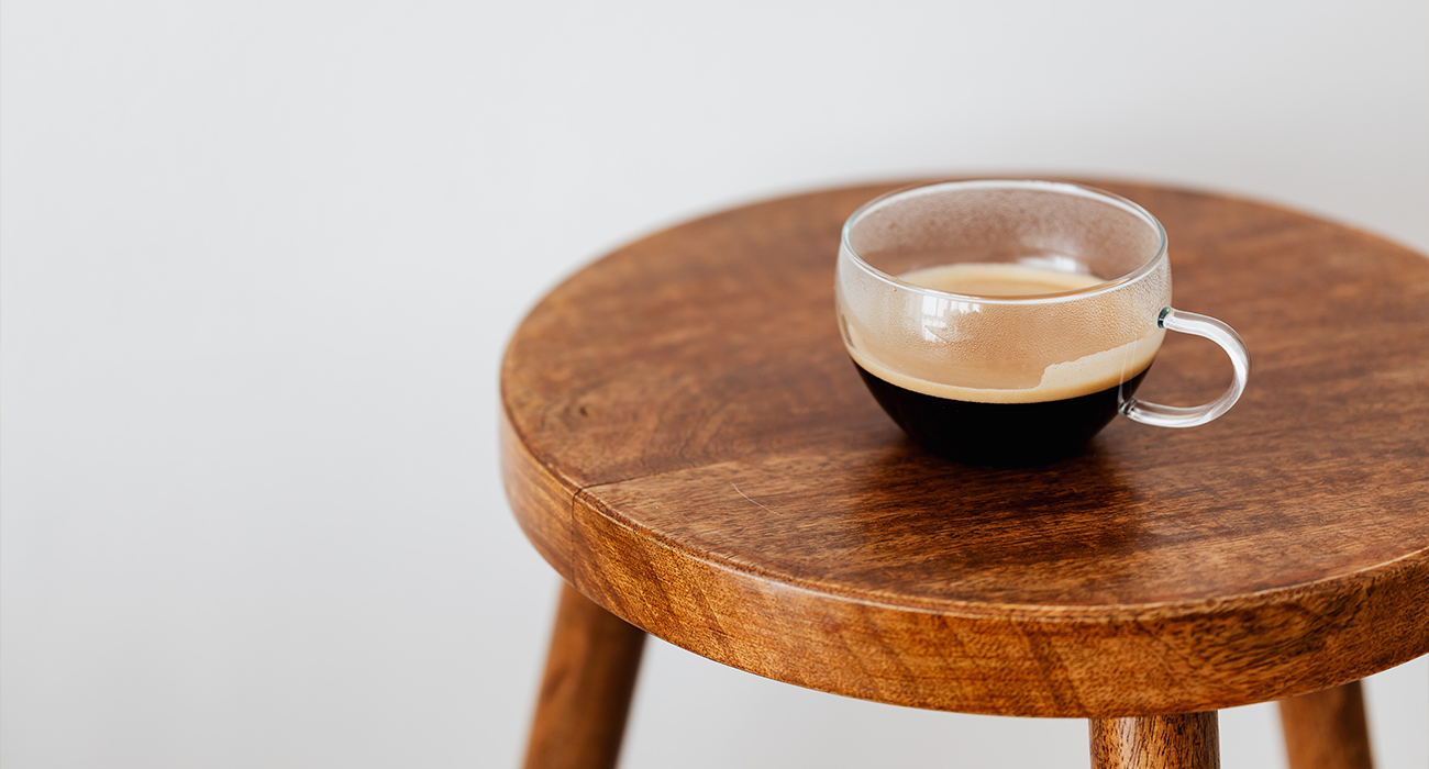 Cup of black coffee on round table.