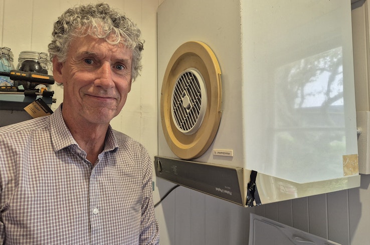 Man next to old clothes dryer.