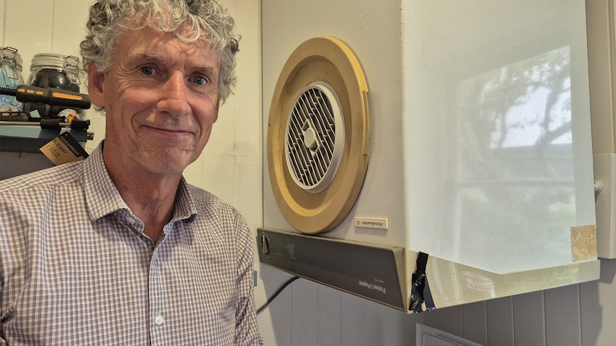 Man next to old clothes dryer.