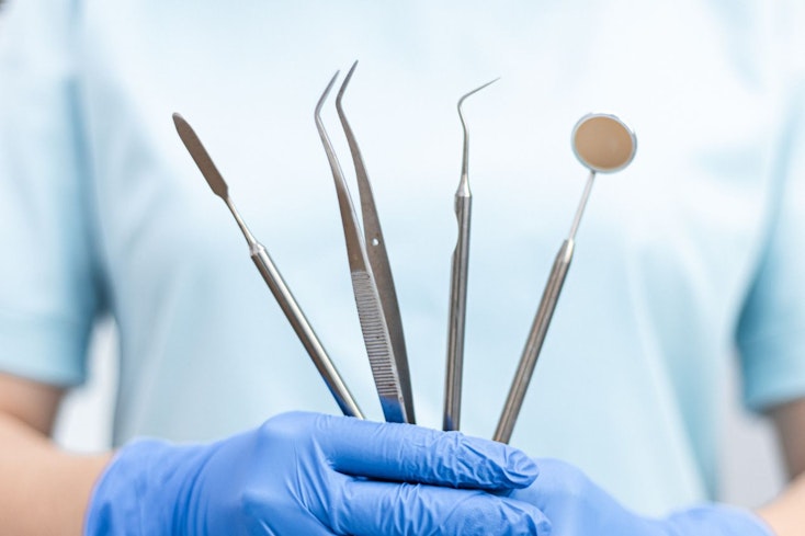 Image of a dentist holding tools
