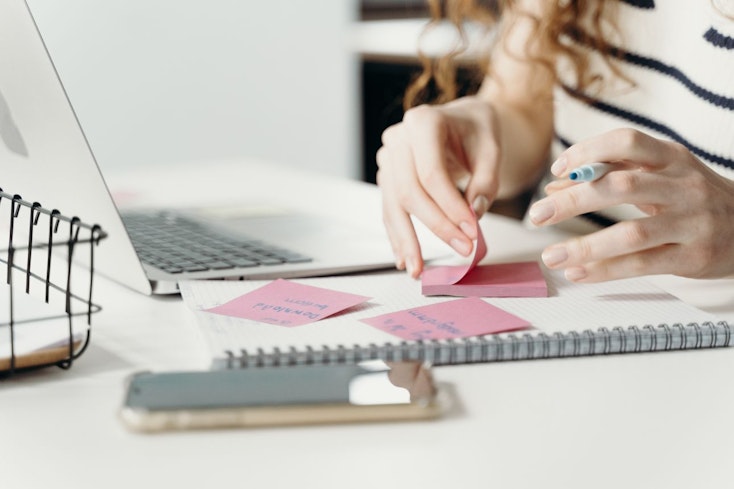 Image of a person writing on a sticky note