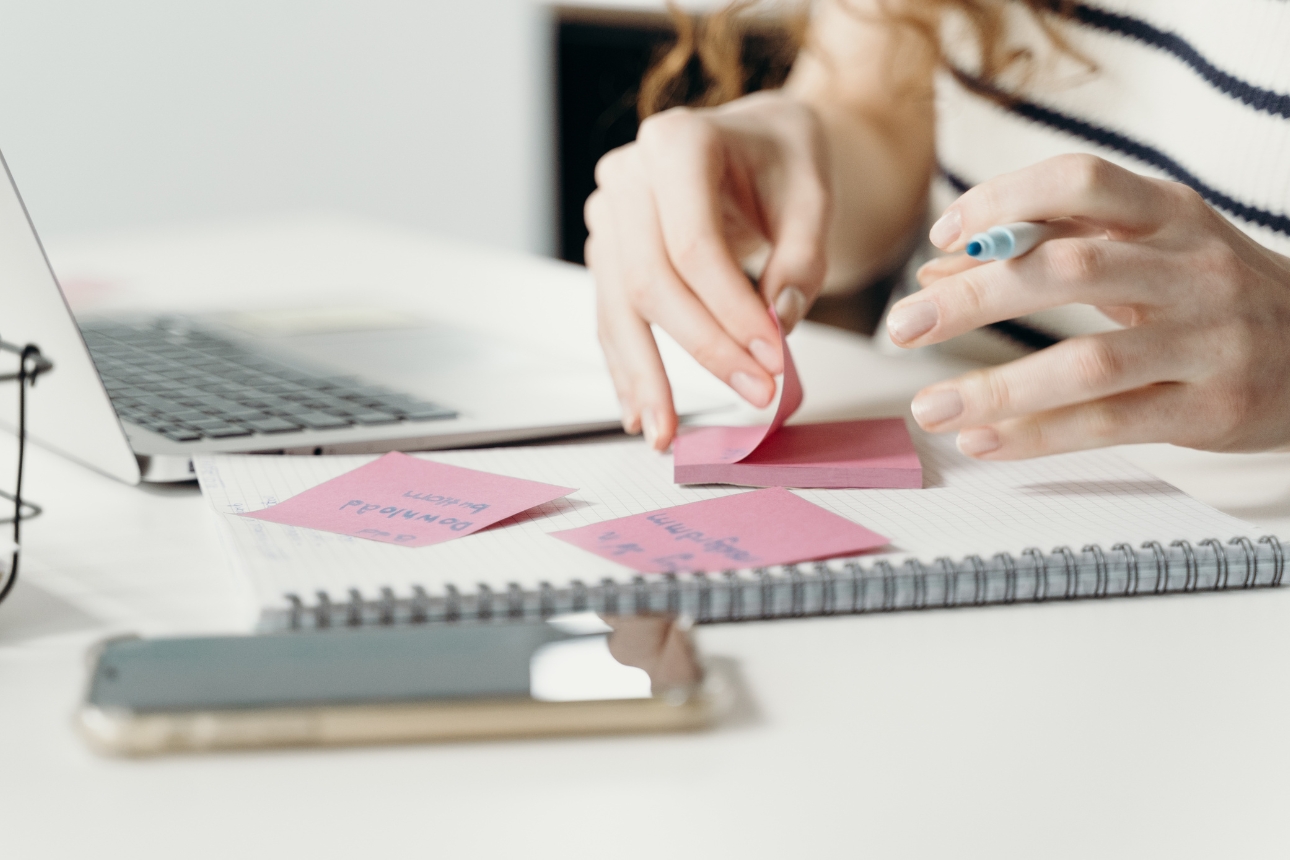 Image of a person writing on a sticky note