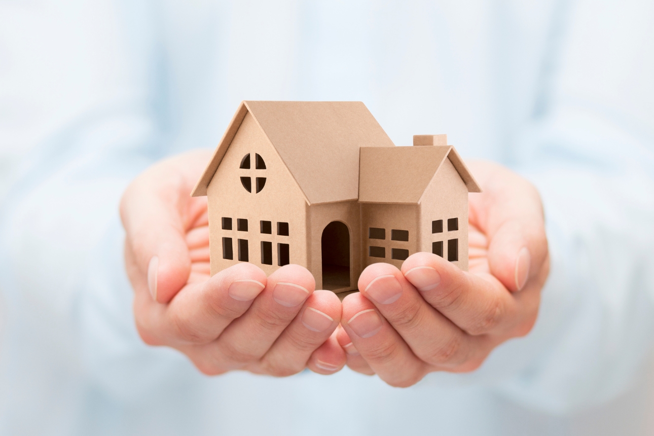 Man holding cardboard house in hands.