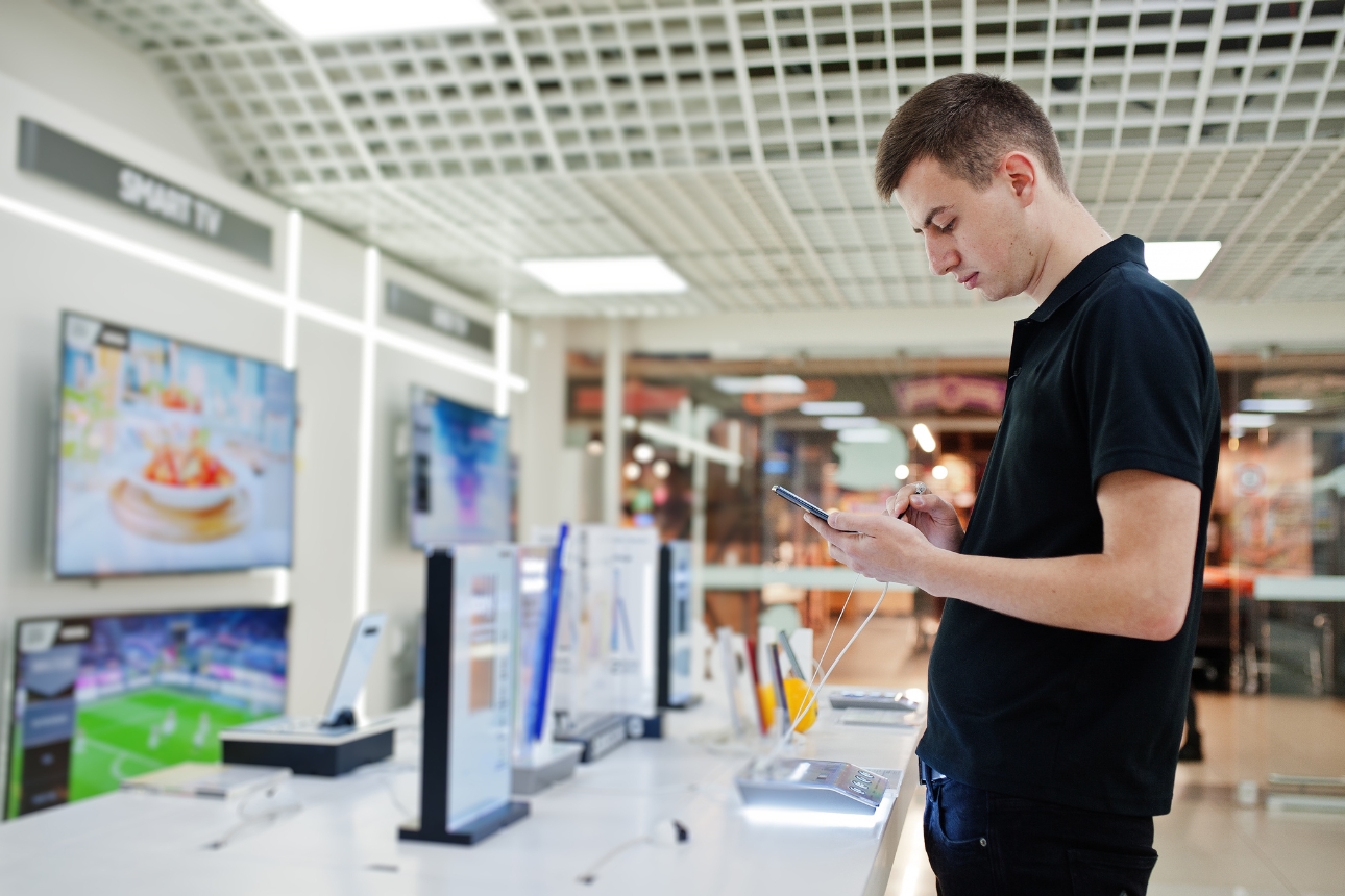 Man looking at phone at a technology store.