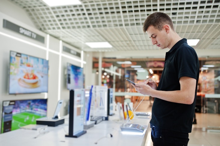 Man looking at phone at a technology store.