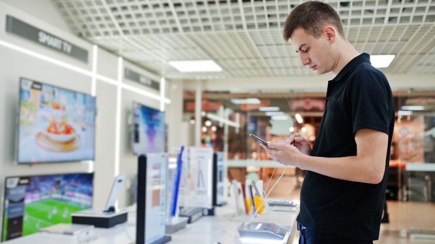 Man looking at phone at a technology store.