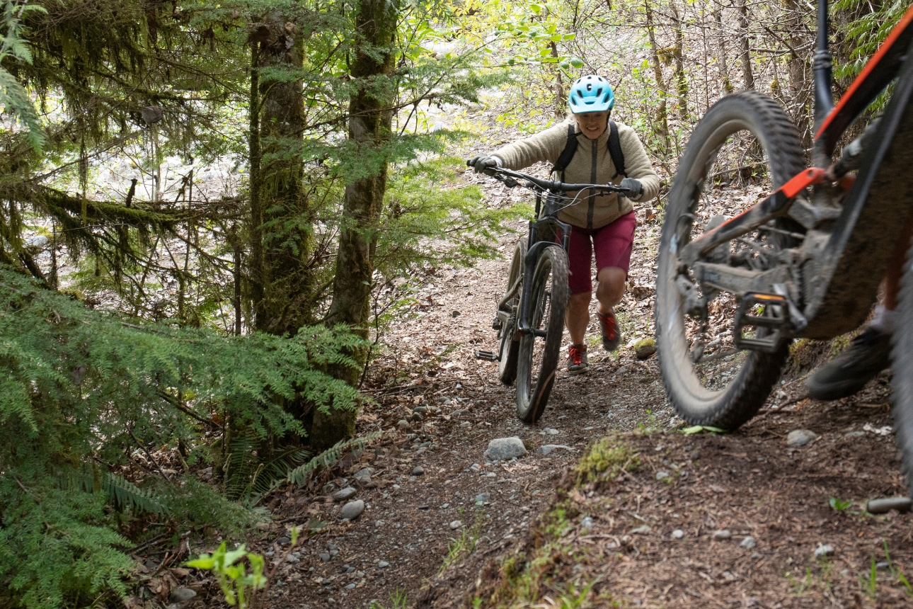 Two people riding e-bikes on a trail.
