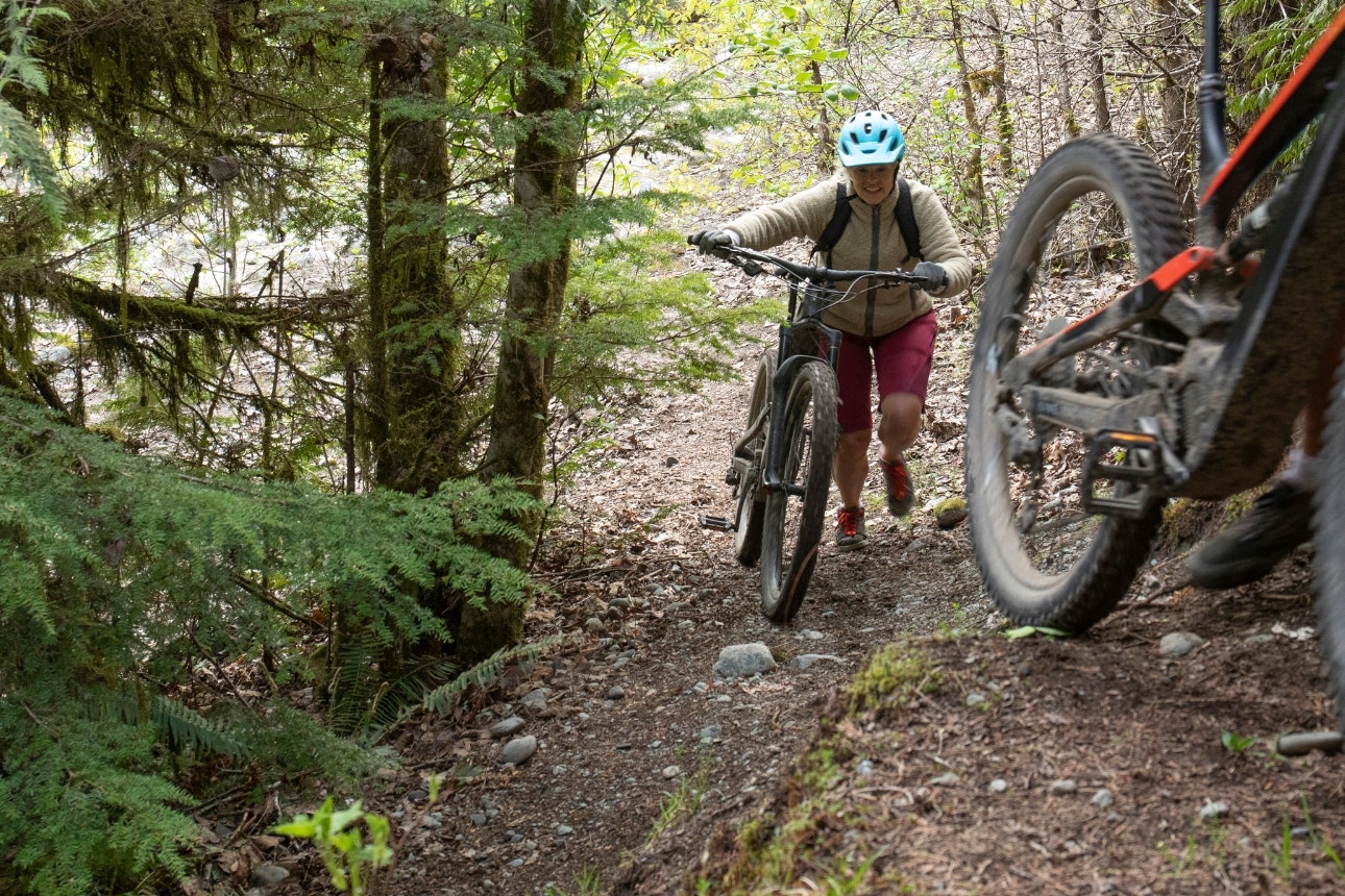 Two people riding e-bikes on a trail.