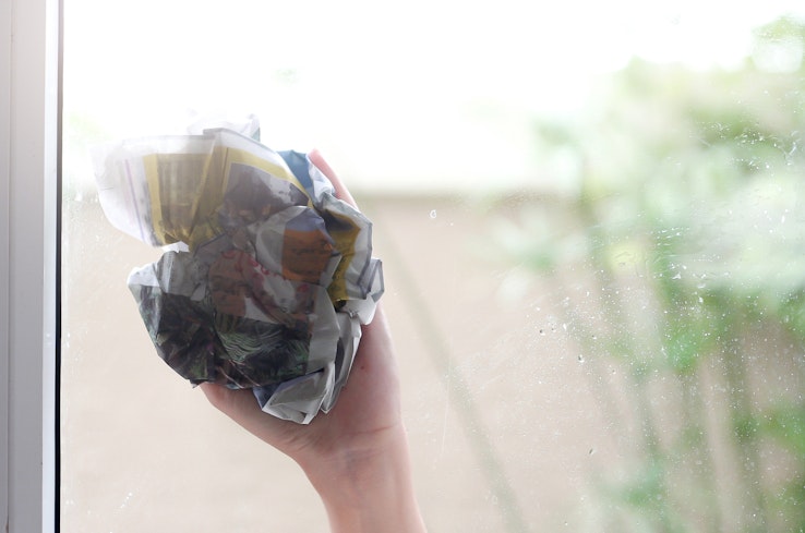 Cleaning window with newspaper.