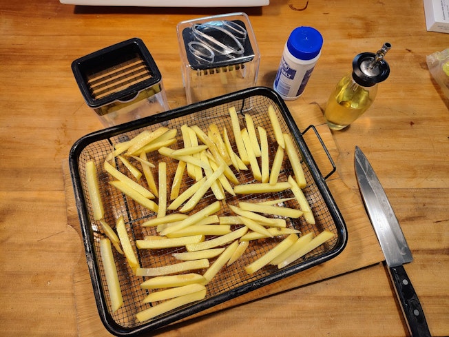 Sliced potato chips in an air fryer basket.