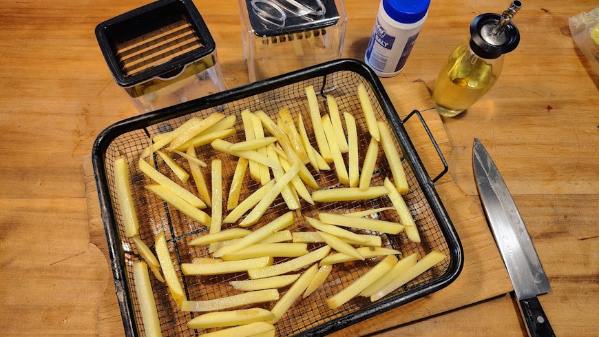 Sliced potato chips in an air fryer basket.