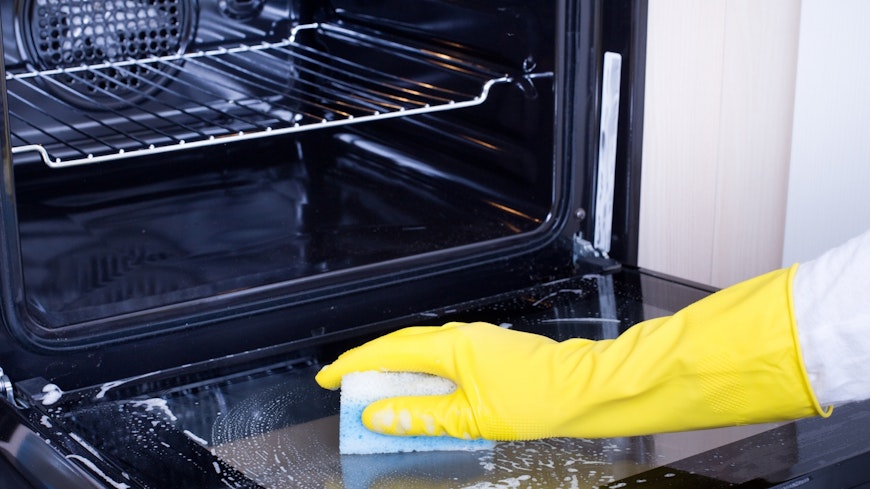 Person cleaning an oven with a sponge.