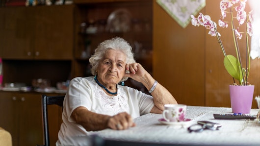 Older woman sitting at kitchen table.